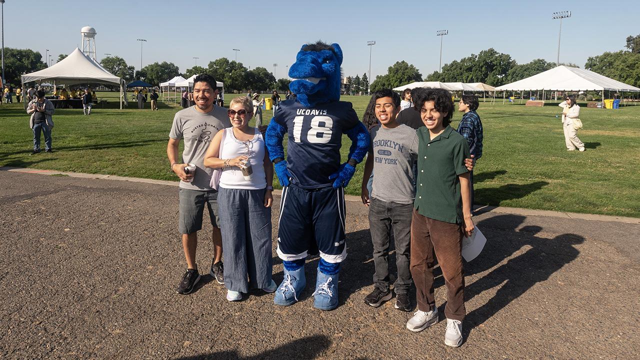 Four people pose with alongside Gunrock for a photo at Hutchinson Field.